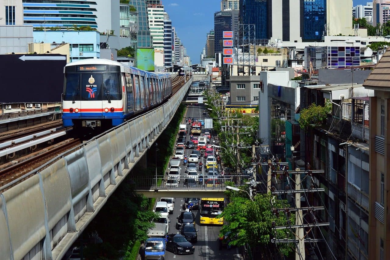 A BTS Skytrain running above a busy road lined with towers