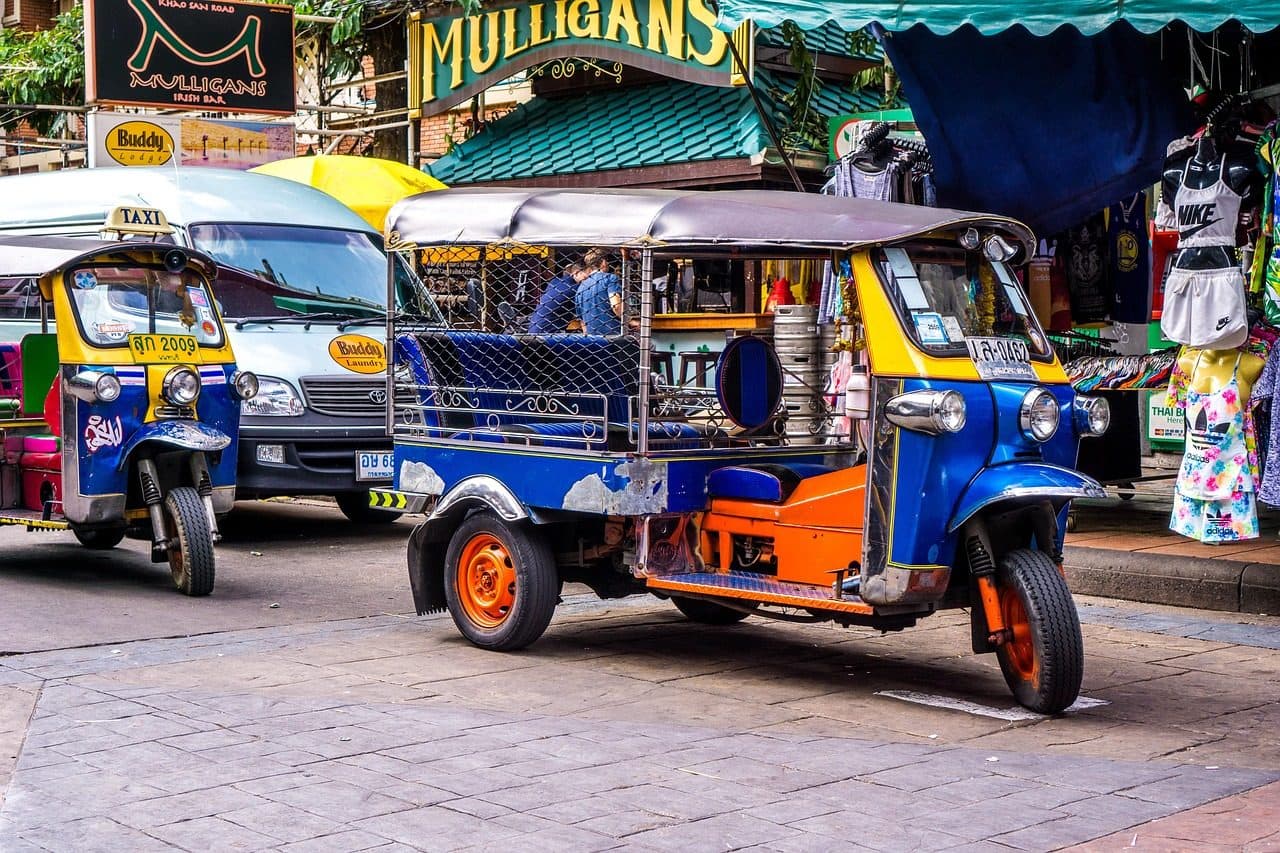 A tuk-tuk parked outside shops and bars on Khao San Road